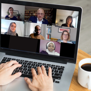 A person watches a laptop showing a recording of a Zoom call